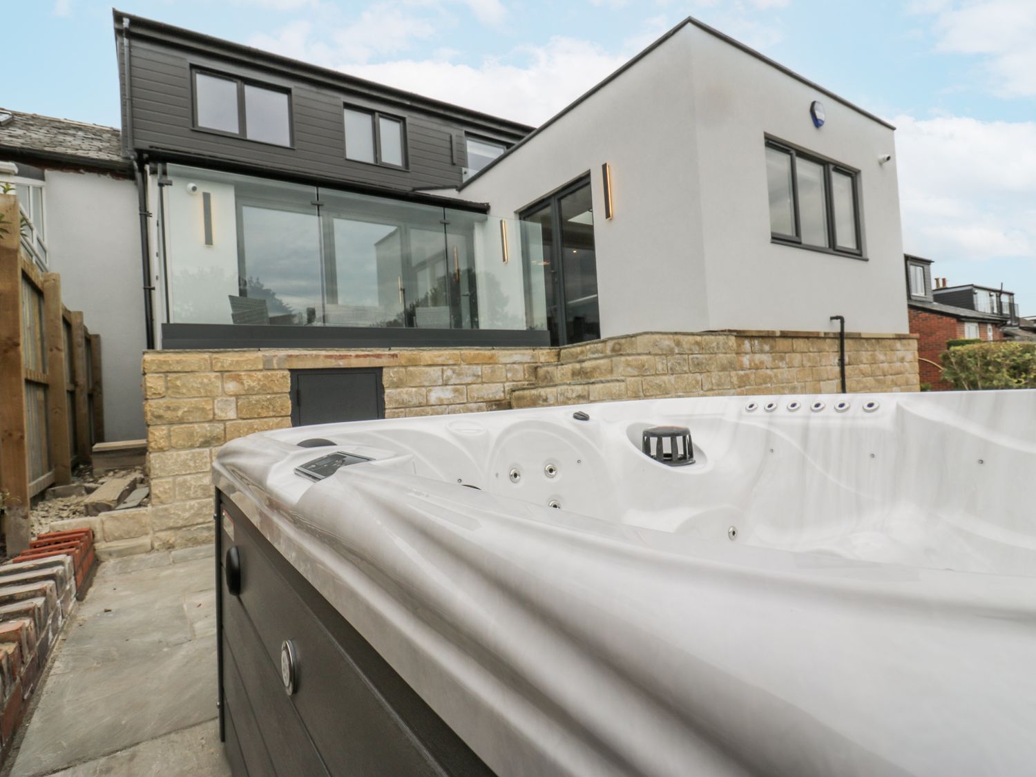 A hot tub with a view of a modern house at Ellis House in Huddersfield