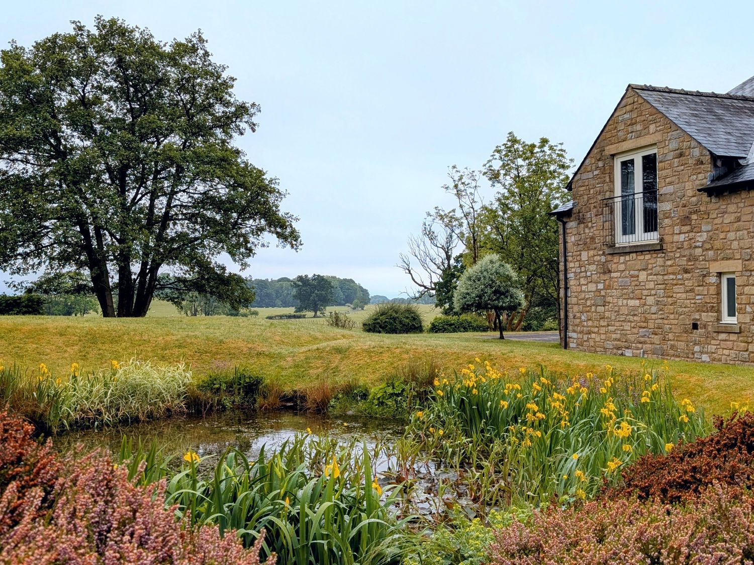 A garden with a pond and flowers at High View Meadows in Kirkby Lonsdale
