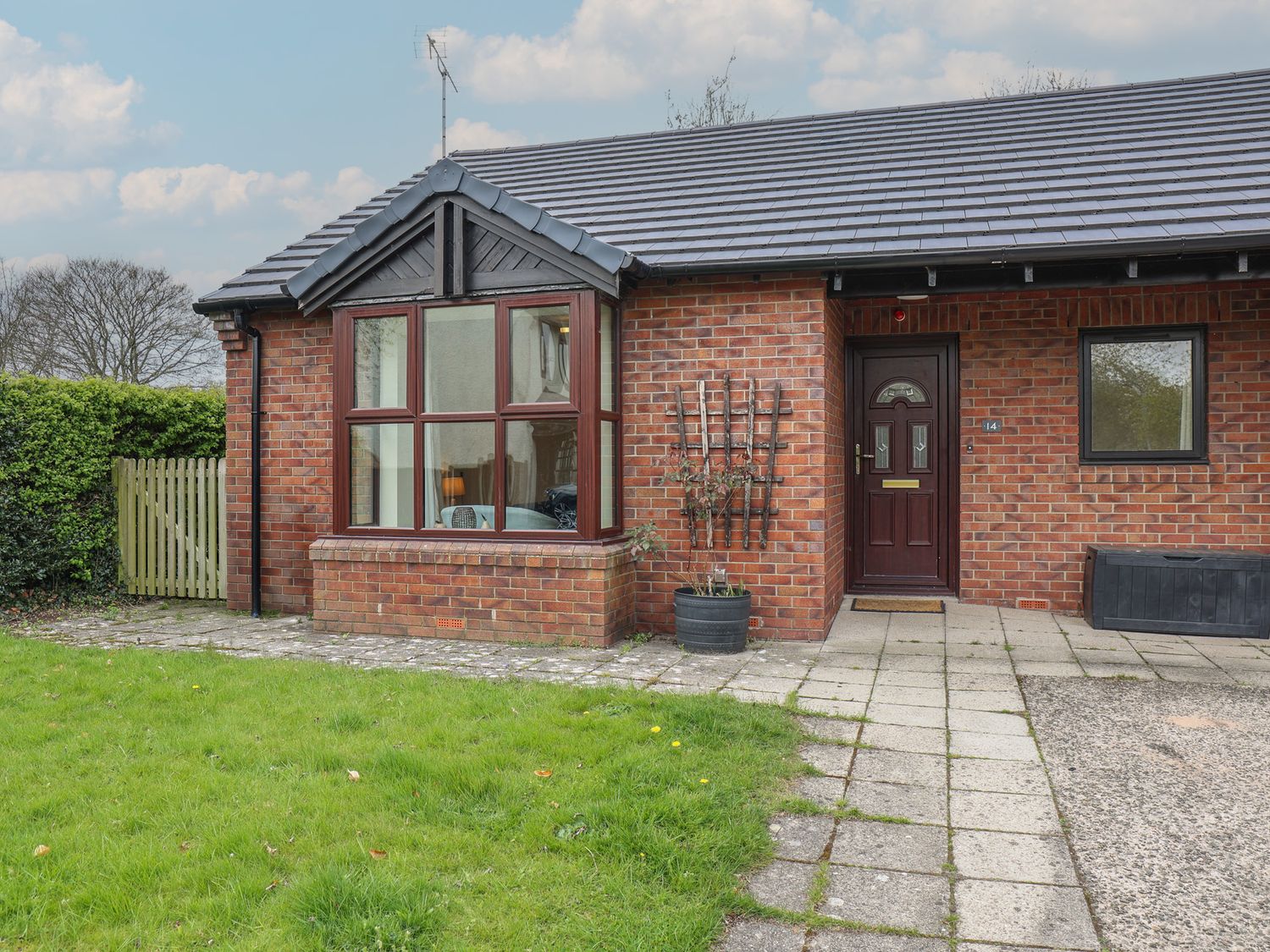 A brick exterior with a pathway and grass at Bungalow 14 Eamont Park Penrith