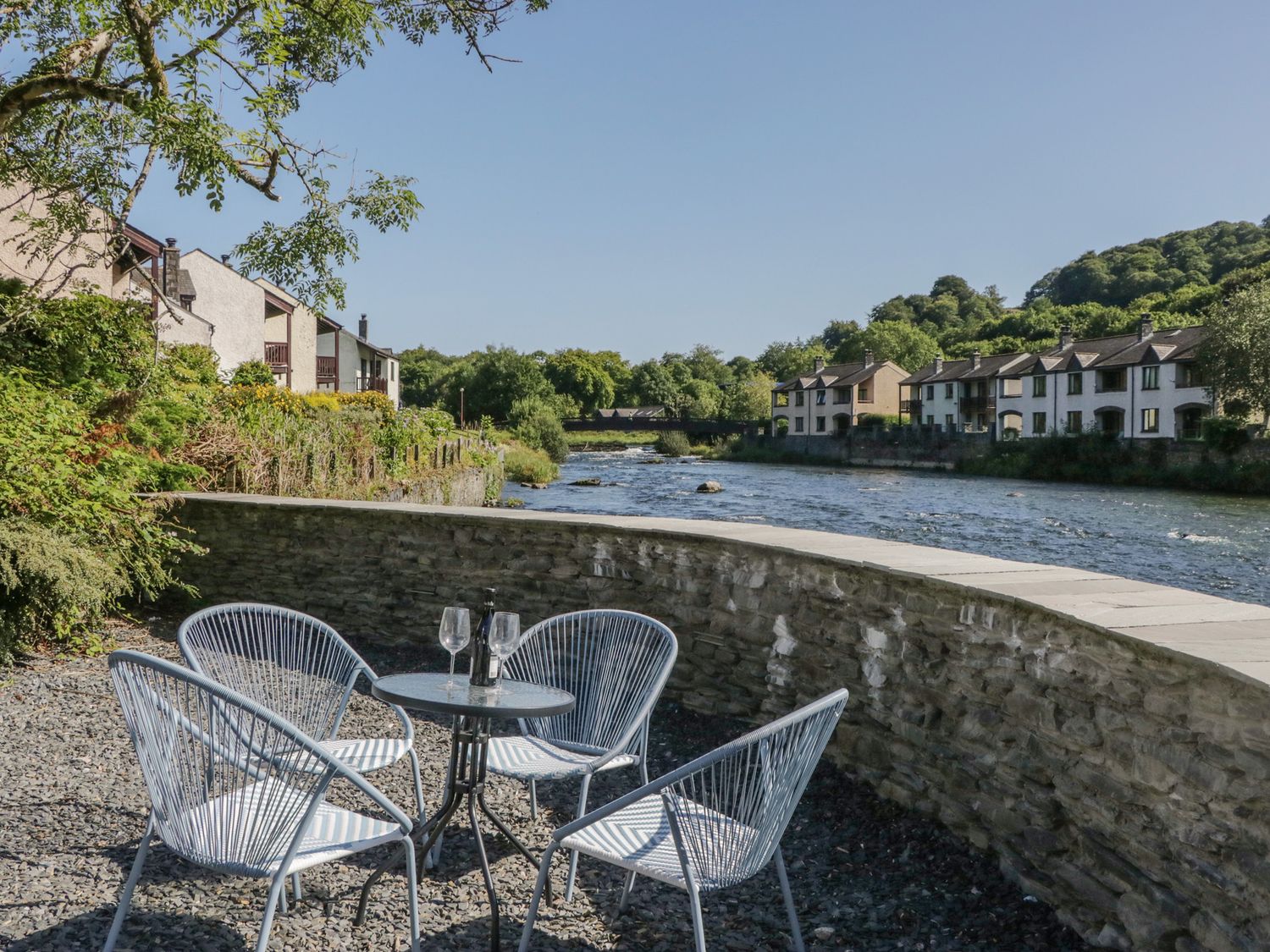 An outdoor seating area by a river at Old Post Office Cottage in Backbarrow near Newby Bridge