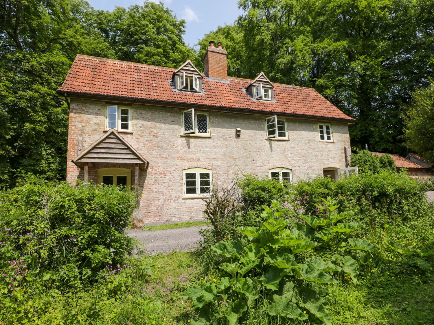 A house with a porch surrounded by greenery at Keepers Cottage in Devizes