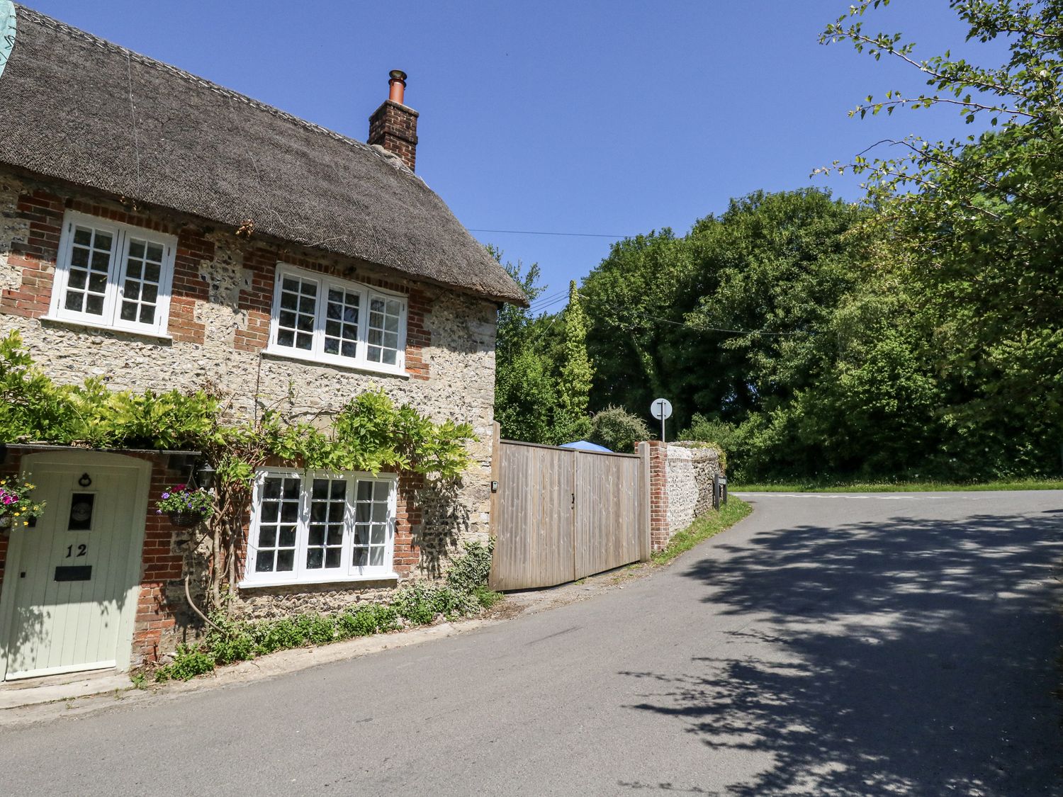 A cottage with a thatched roof and a garden at Happiness Cottage in Piddlehinton