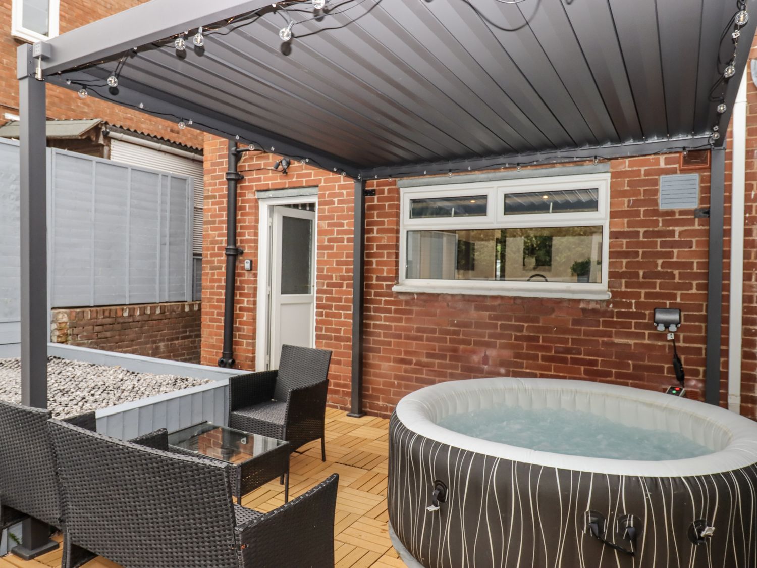 An outdoor area with a hot tub and seating at Milana Tiverton