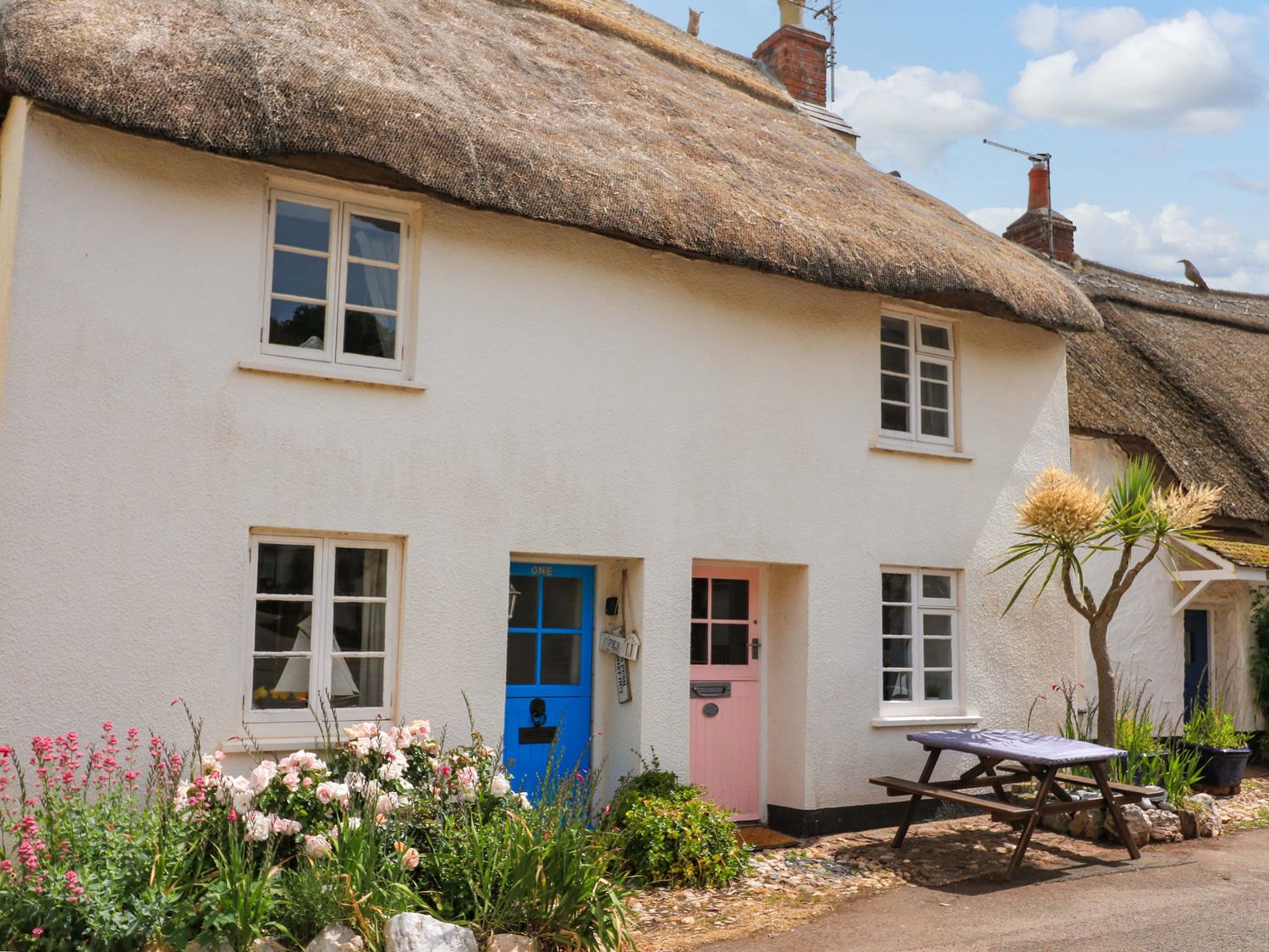 A cottage with a thatched roof and flower garden at 1 The Square Hope Cove