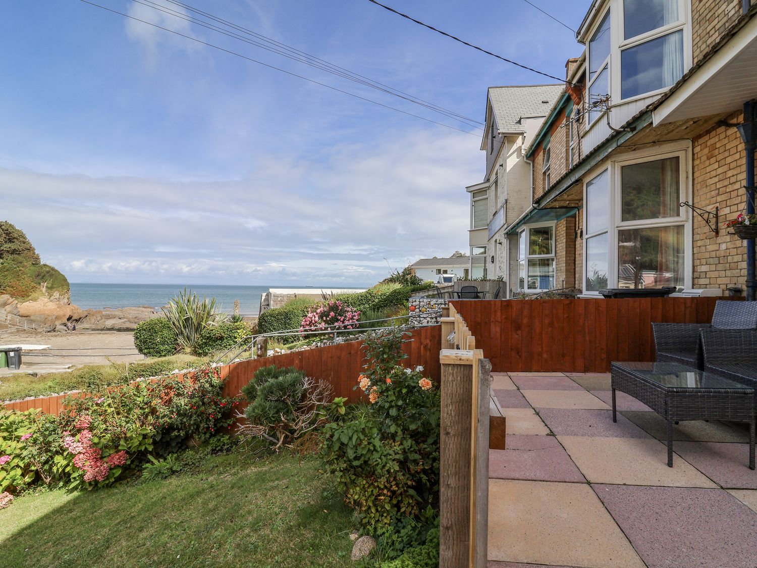 An outdoor seating area with flowers and ocean view at Zide the Zea, Hele Bay, Ilfracombe