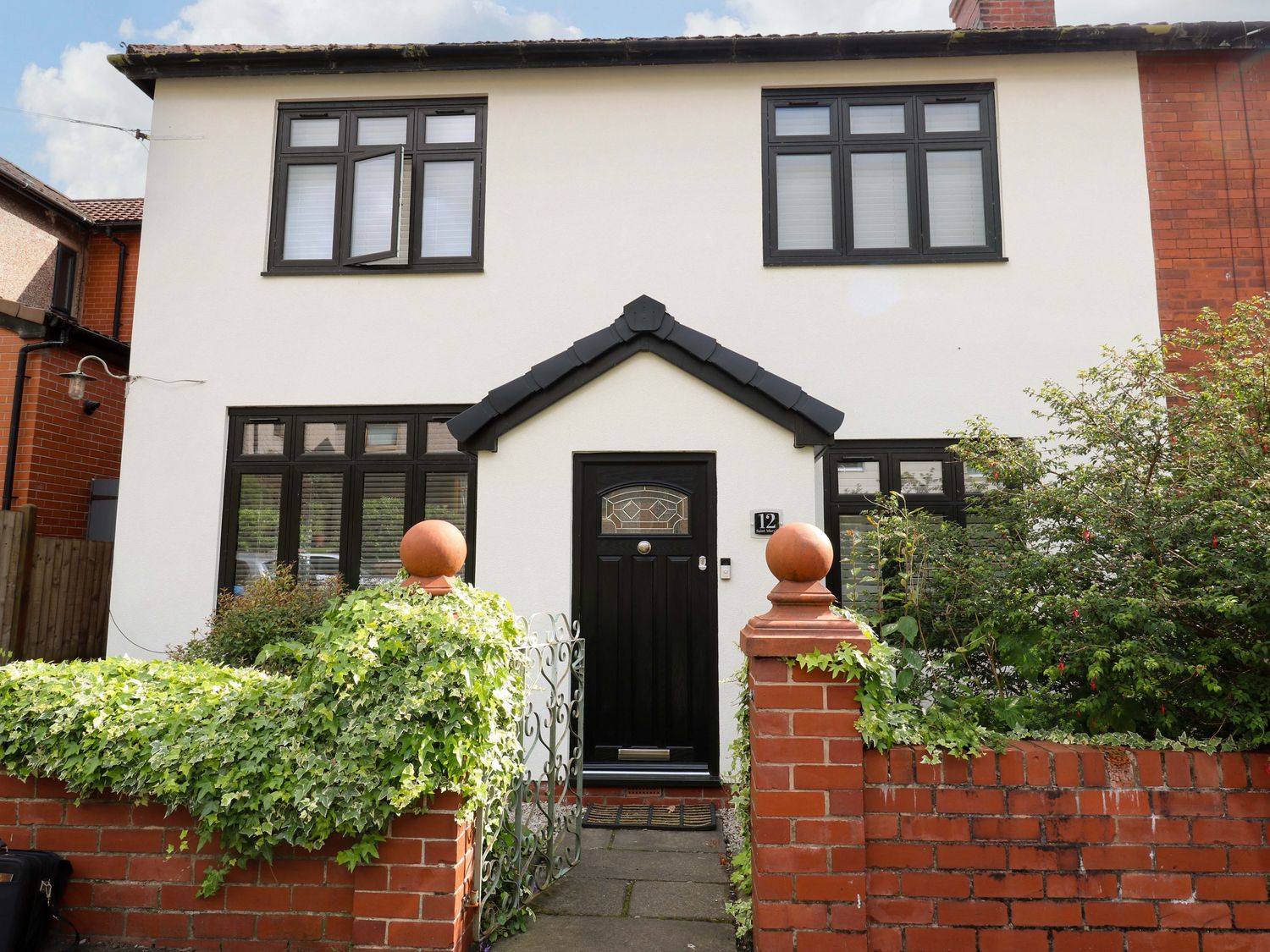 A front view of a house with a black door and windows at St Mary's House in Oldham