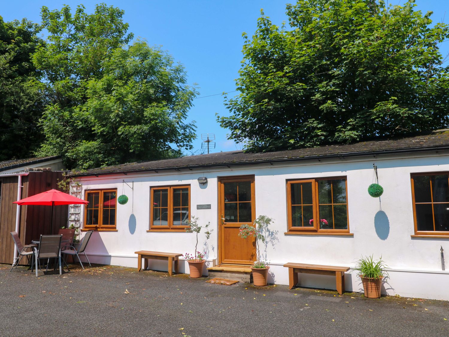 A house with windows and a door alongside a seating area at The Cow Shed in 