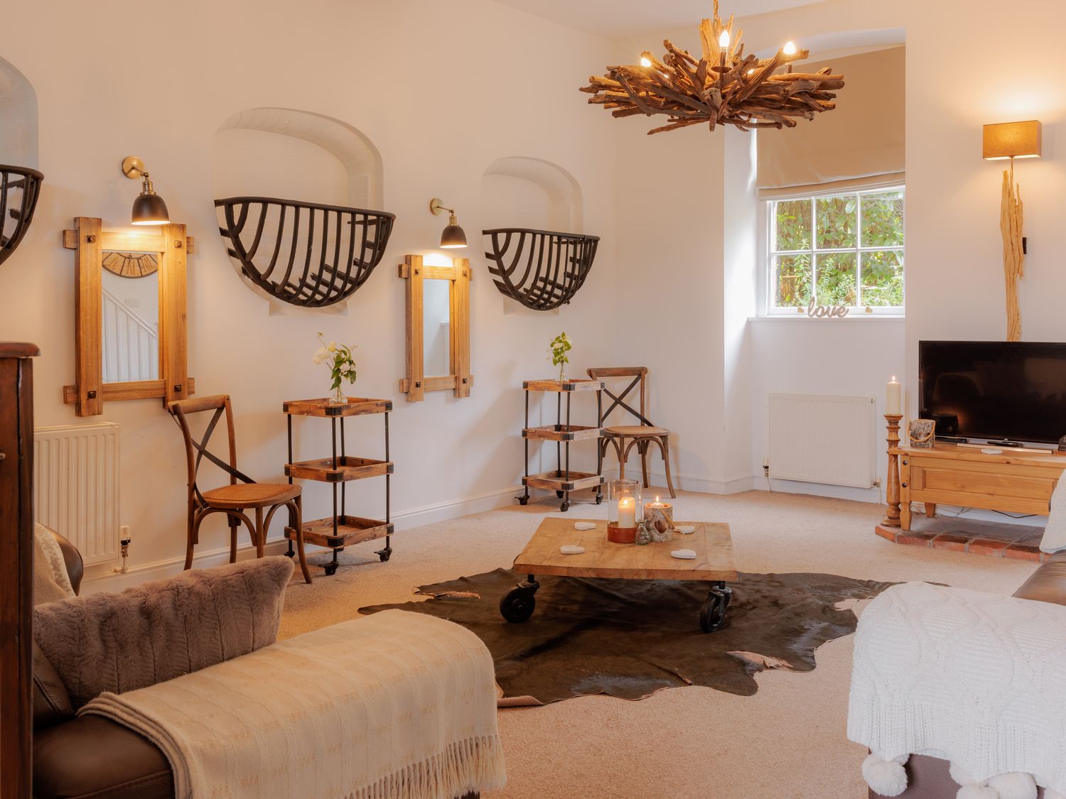 A living room with a chandelier and a television at Stable Cottage in Bridgnorth