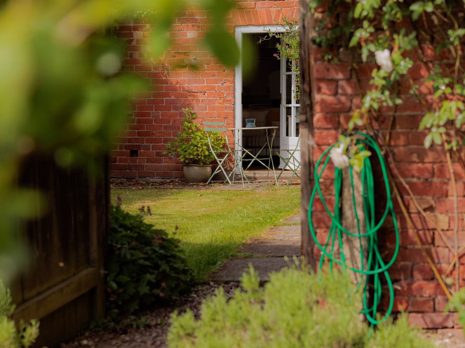 A garden with a table and chairs near a brick wall at The Bothy in Bridgnorth