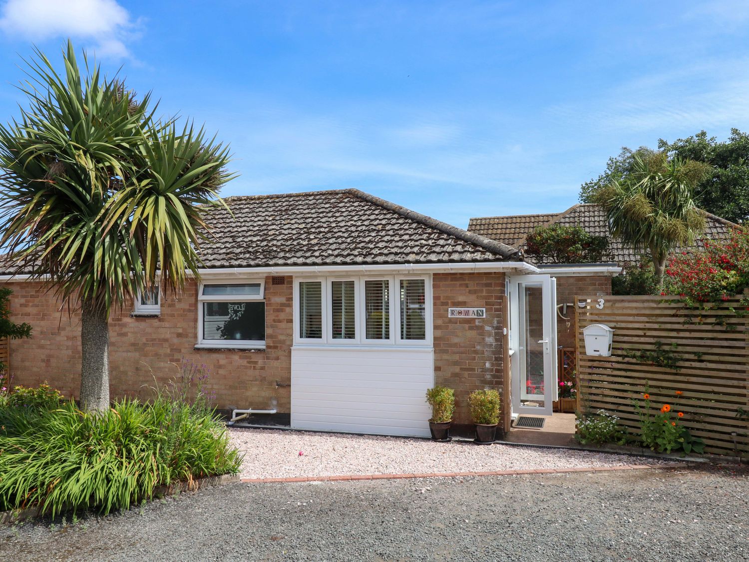 A house entrance with plants and a gravel driveway at Rowan in Brixham