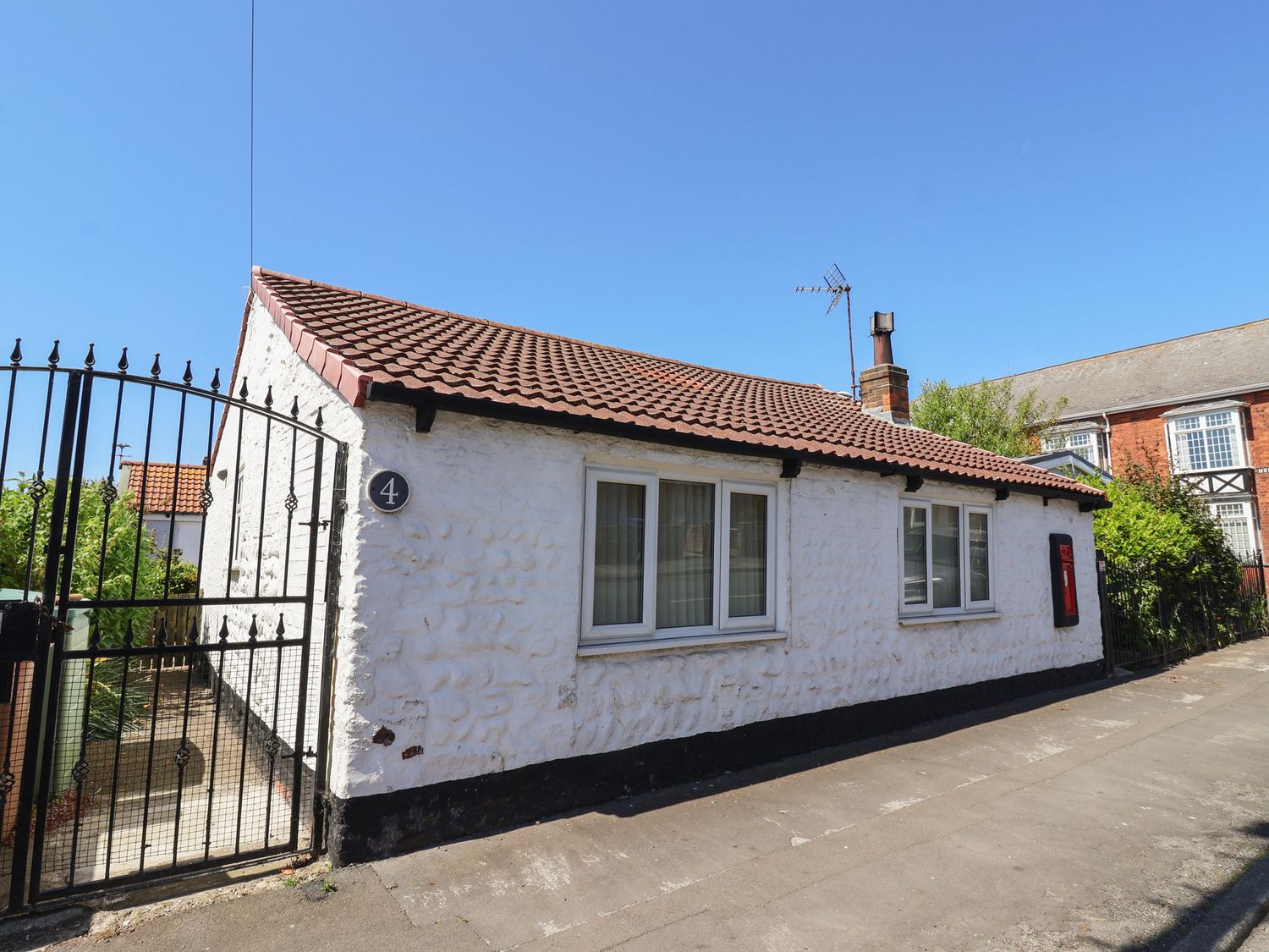 A white single-story house with a tiled roof and black iron gate at 4 Queen Street in Withernsea