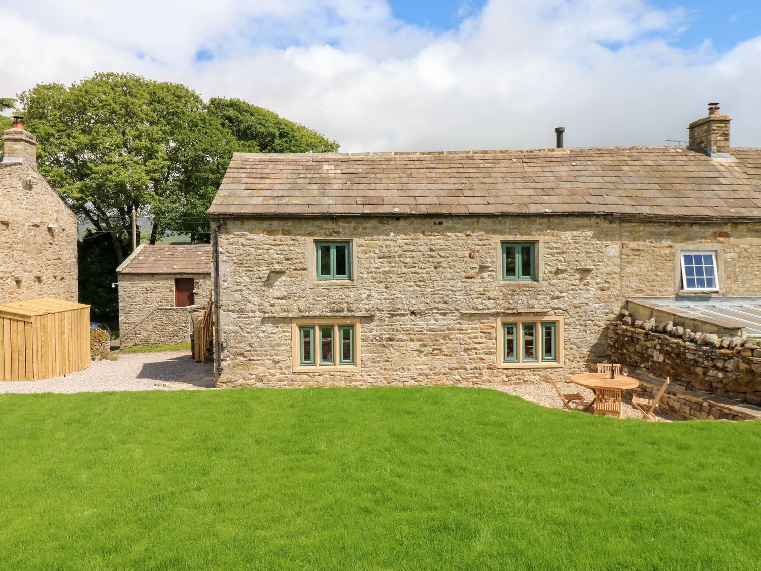 An outdoor area with a stone building and garden furniture at High Meadow Barn Thornton Rust near Bainbridge