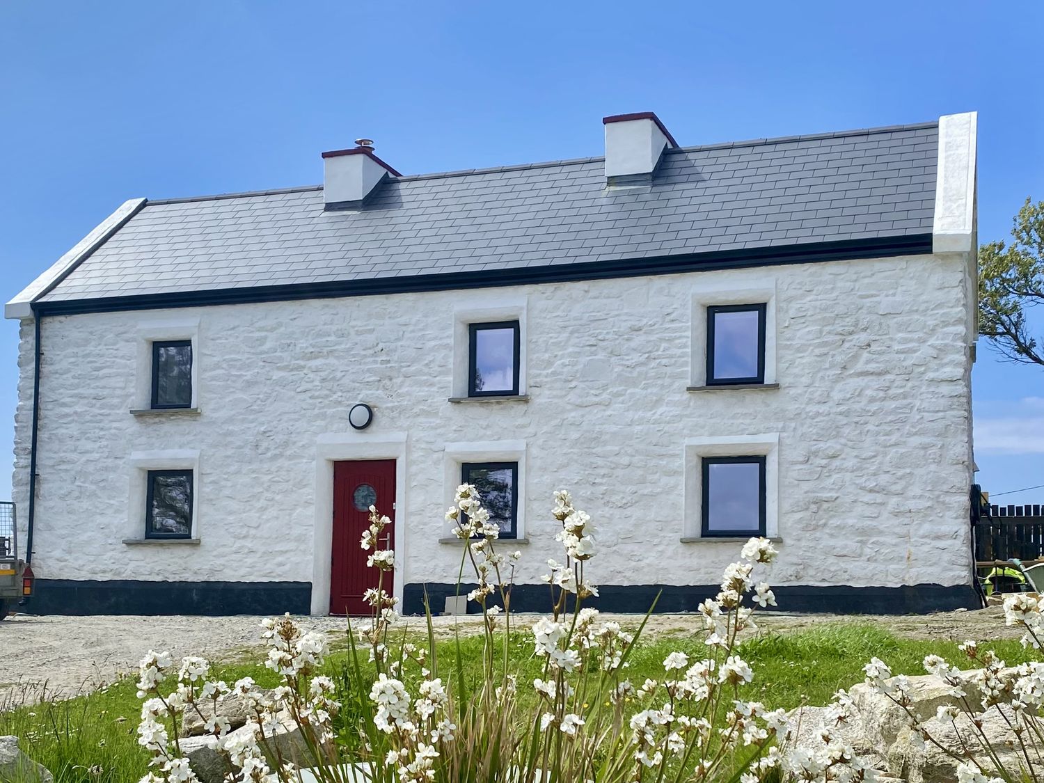 A house with a red door and windows at Nead na bhFáinleog (Swallows’ Nest) Claddaghduff, County Galway
