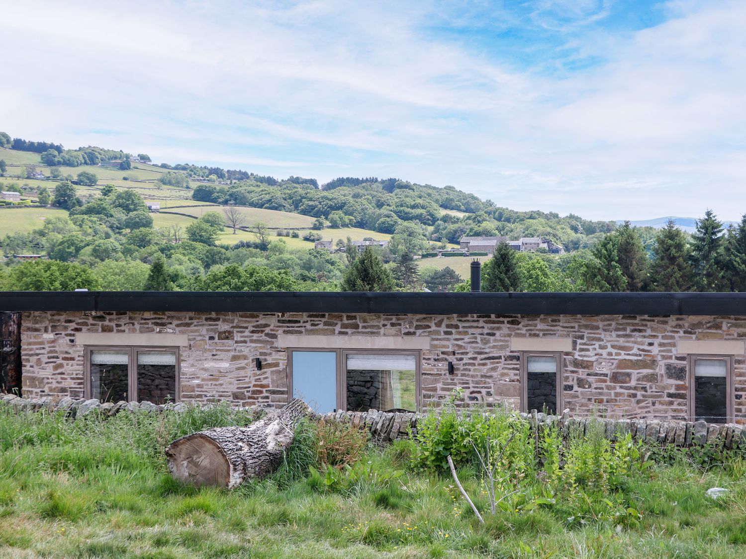 A stone building with windows and grass in the foreground at The Stables in Stockport