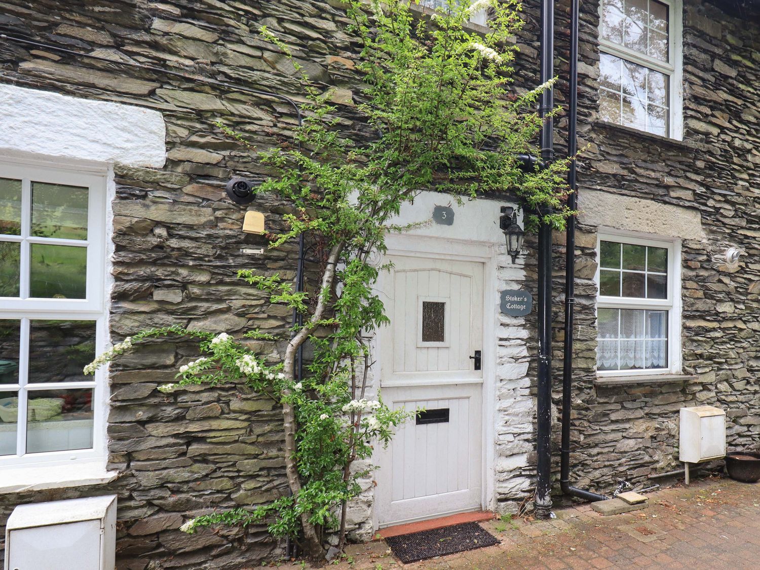 An entrance with stone wall and door at Stoker’s Cottage Bowness-On-Windermere