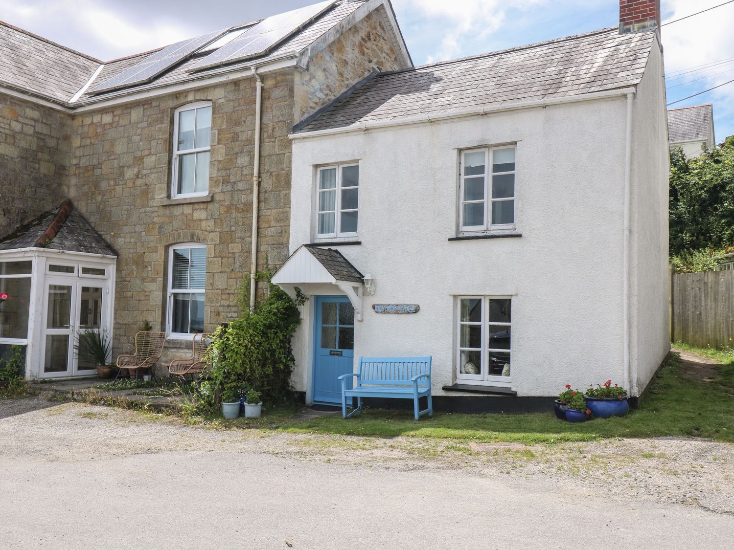 A house with a blue bench and plants at Driftwood Cottage in St. Austell