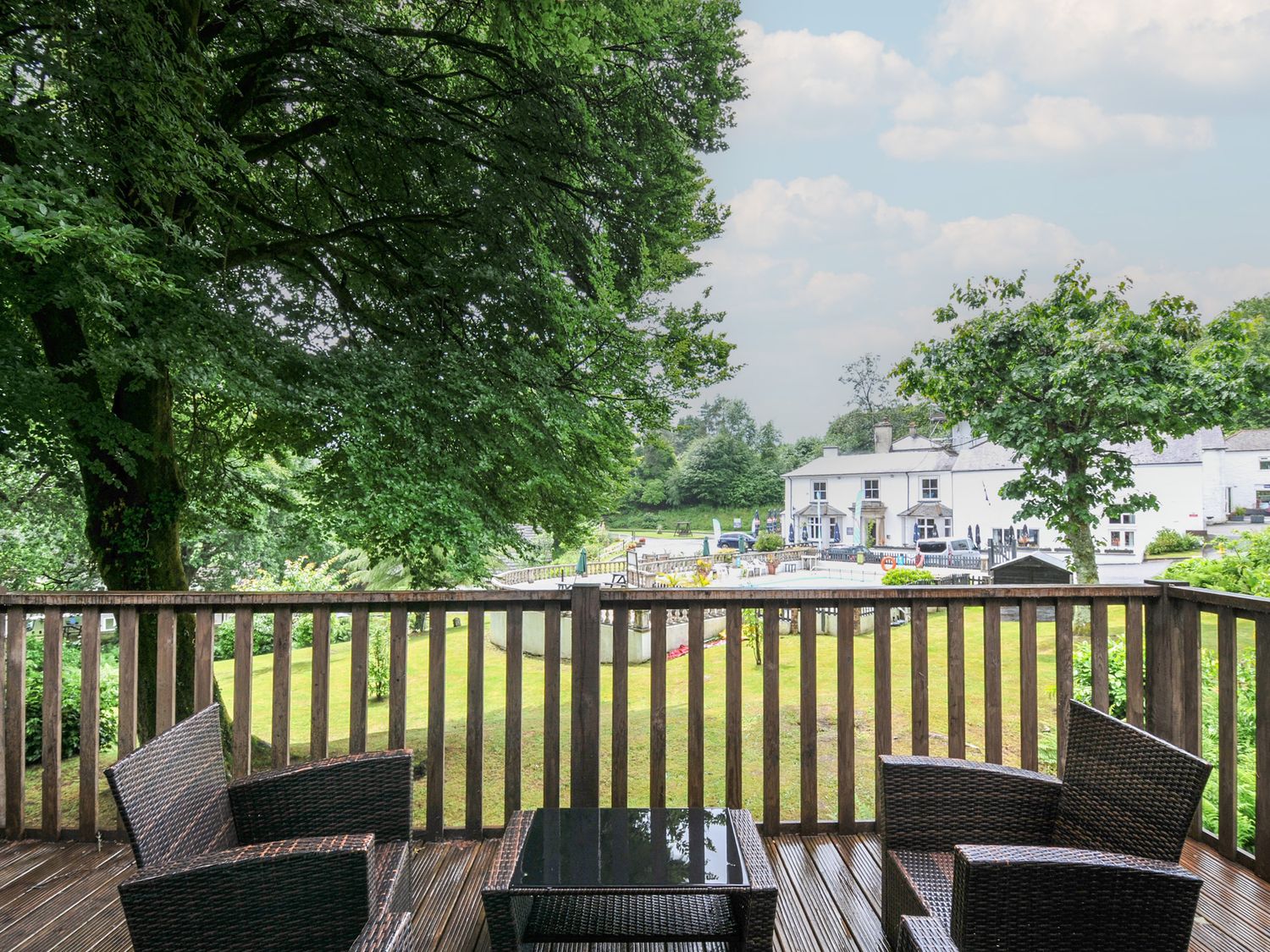 A deck with chairs and a table overlooking a garden at Valley Lodge 2 Callington