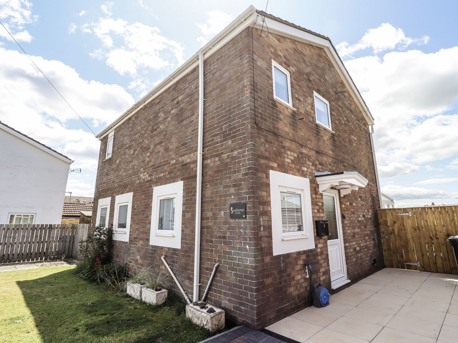 A brick house with a garden and pathway at Seahorse Cottage in Chathill
