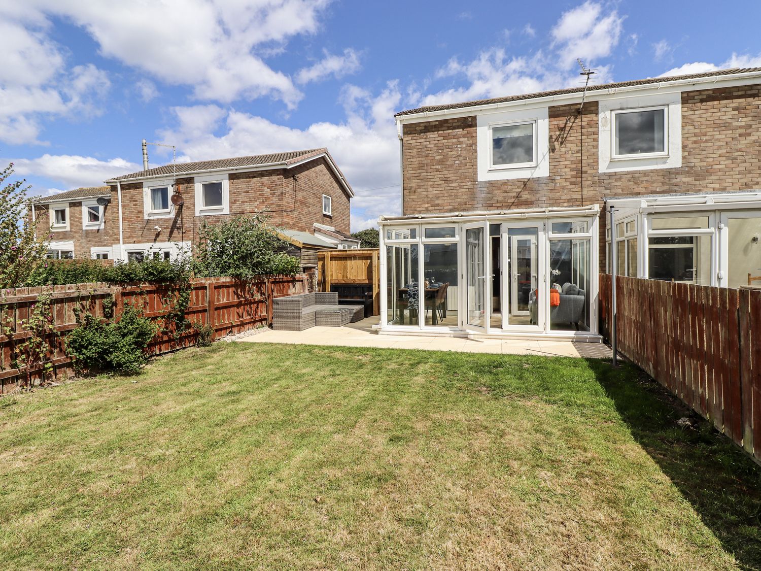 A garden with a house and patio area at Seahorse Cottage in Chathill