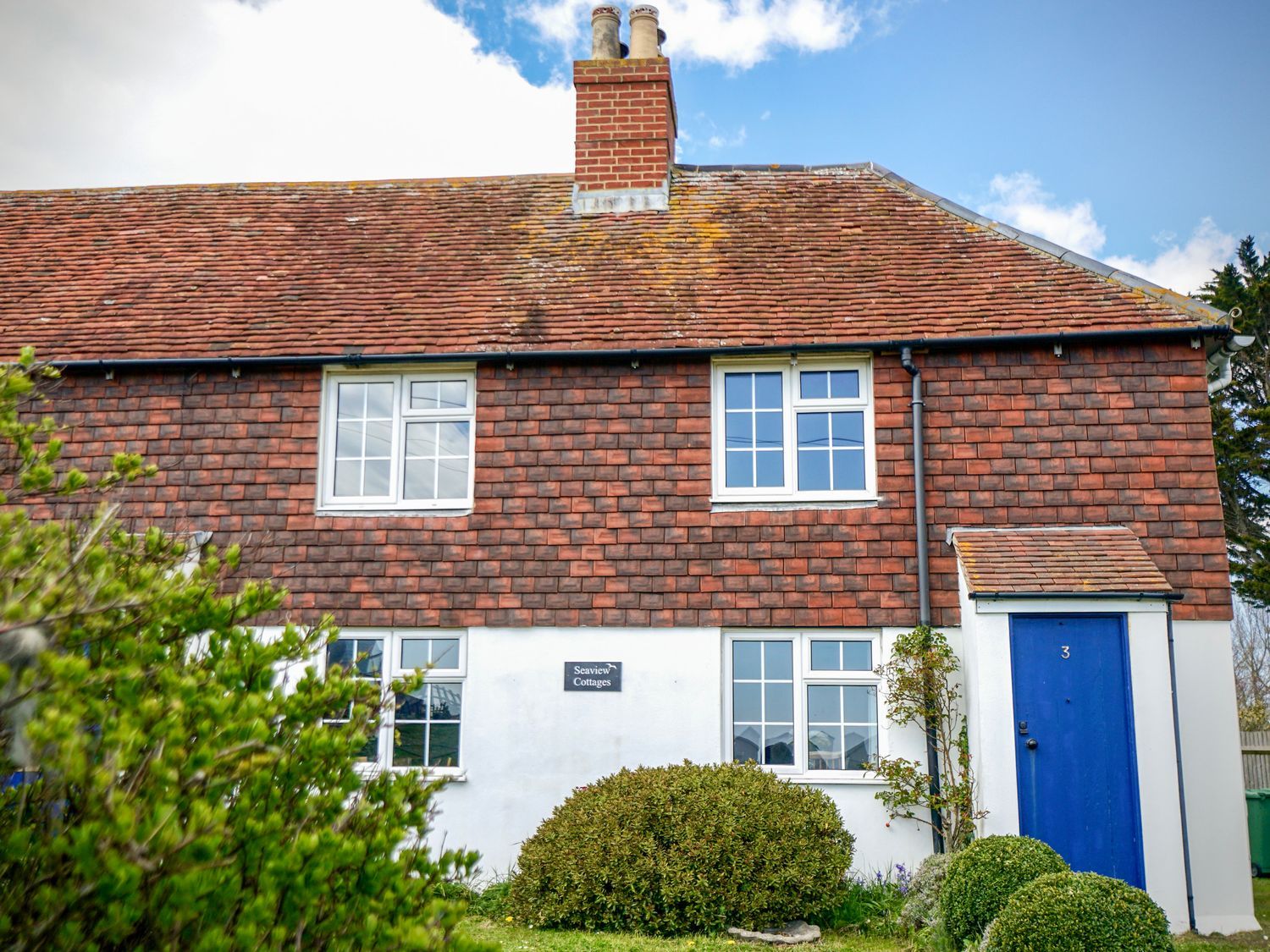 A house with a blue door and windows at Seaview Cottages in Normans Bay near Bexhill-on-Sea