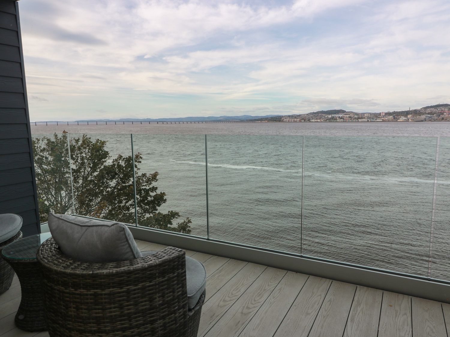 A balcony with chairs and table overlooking water and bridge at Lazy Bulldog in 