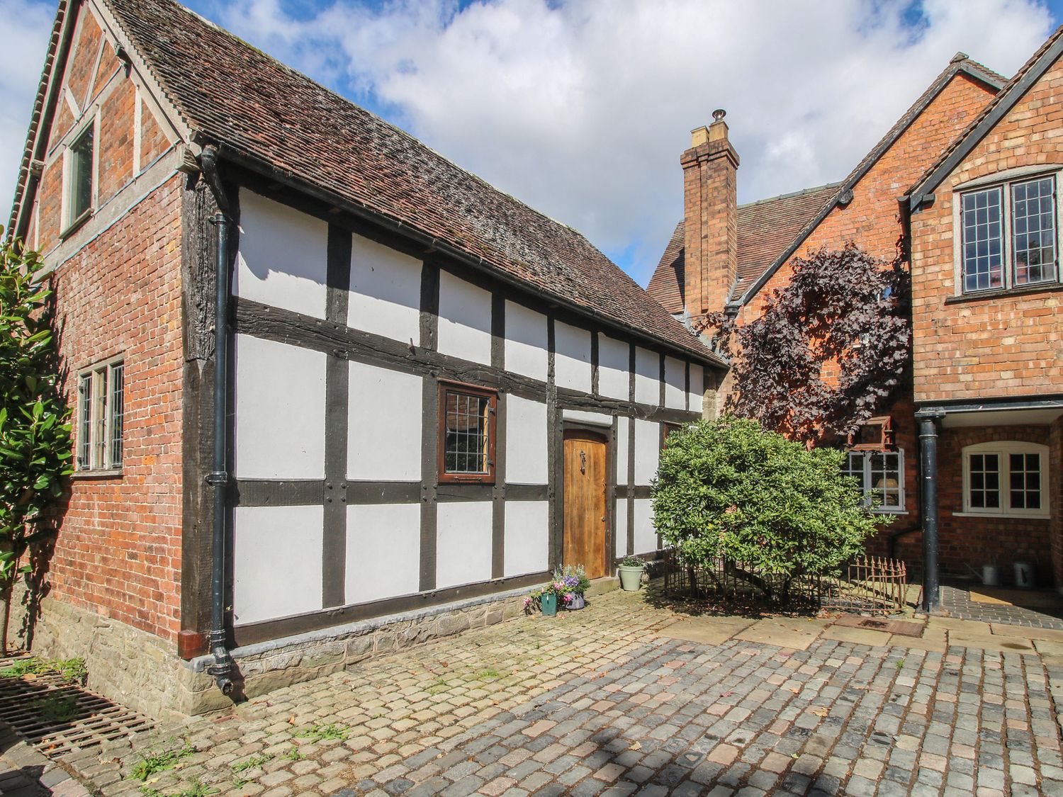 An outdoor view of a brick and timber framed building at Courtyard Cottage Little Stretton