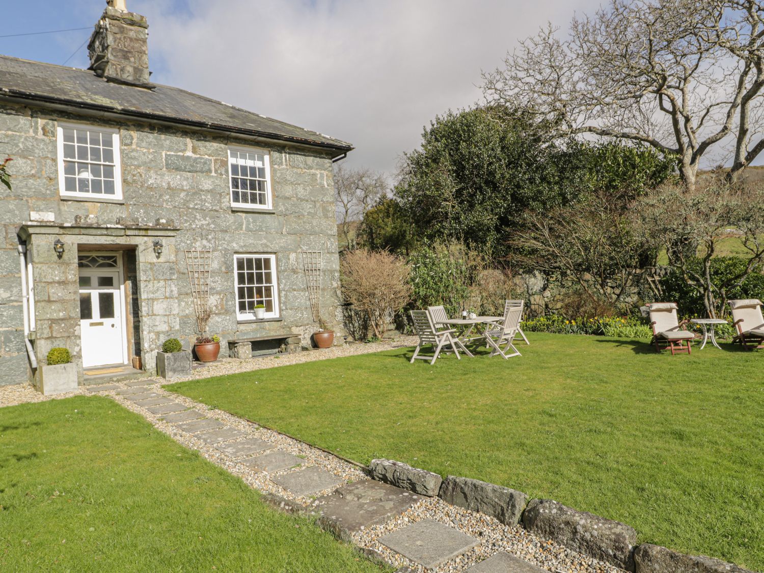 A garden with a house, chairs and a table at Bwthyn Morse in Llanfair
