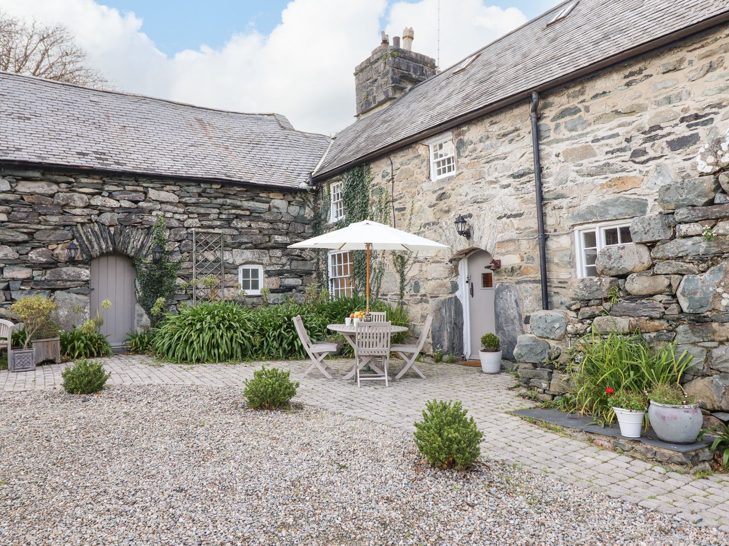 An outdoor seating area with a stone wall at Bwthyn Canol in Llanfair