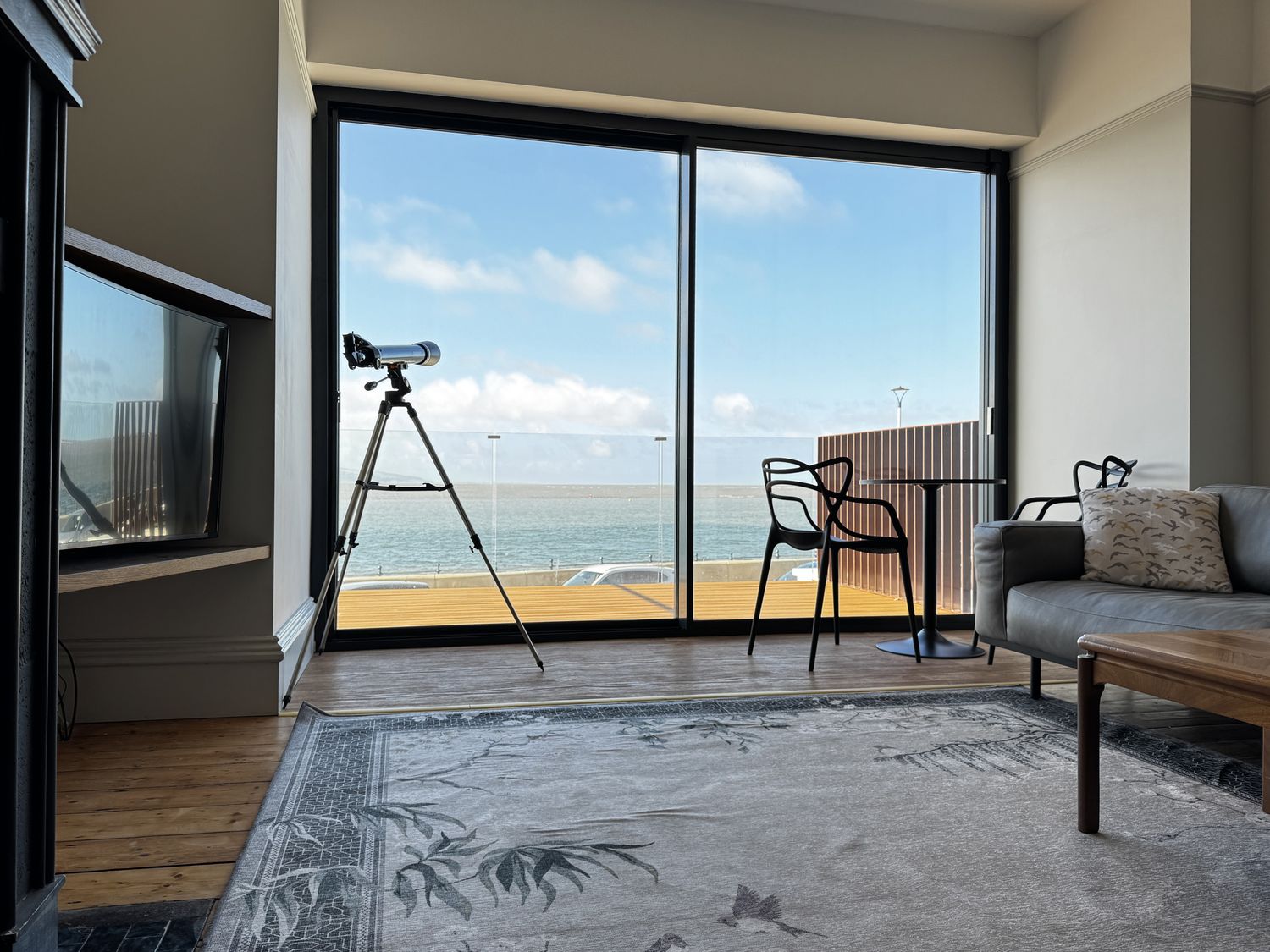A living room with a telescope and a view of the water at Mostyn View in West Kirby