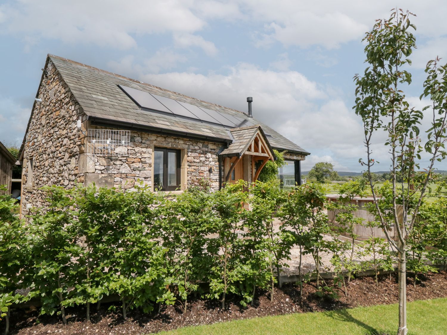 A stone house with solar panels and plants at Lindeth Croft in Carnforth