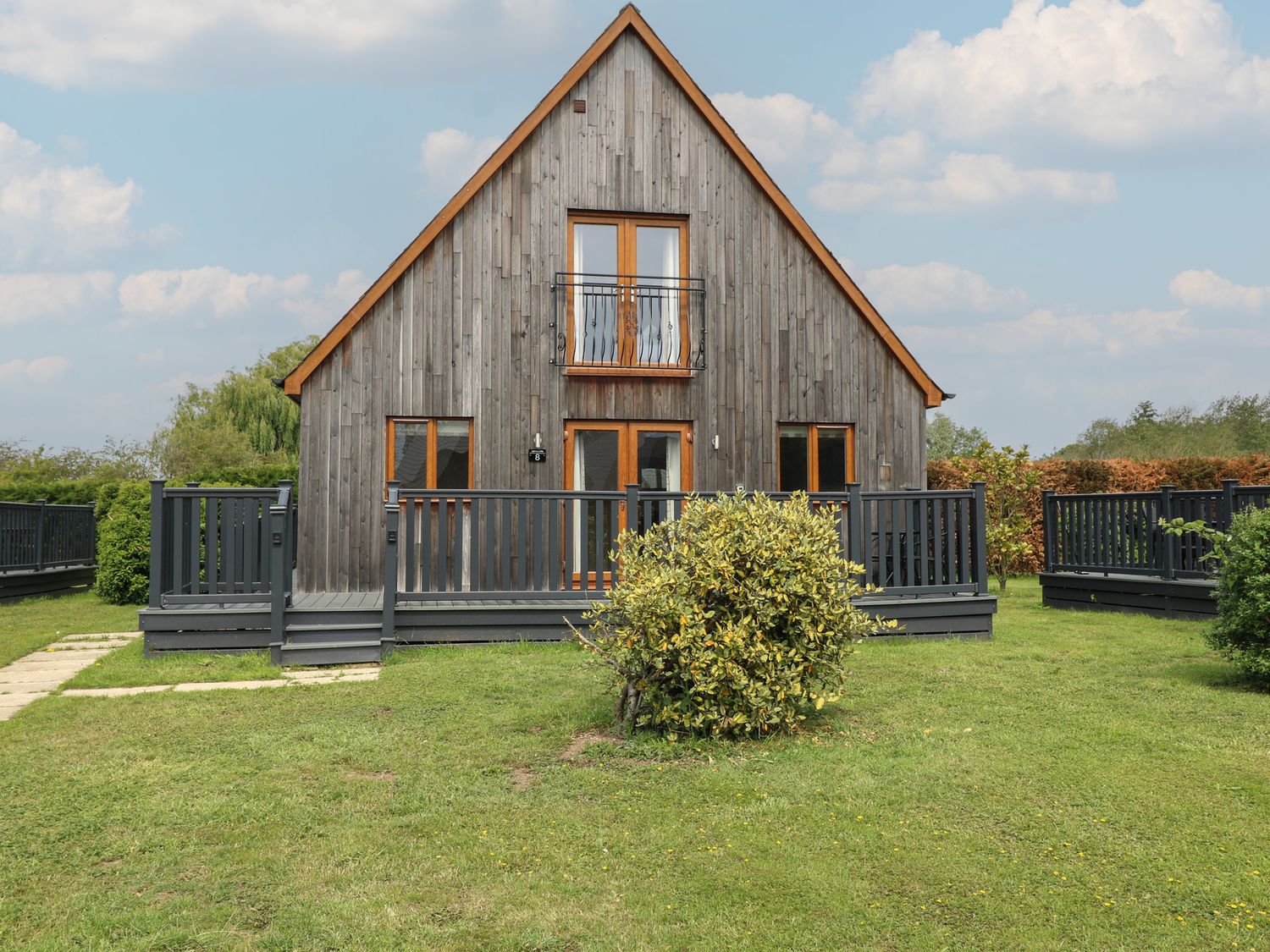 A house with a wooden exterior and decking at Lodge 8 in Brigg