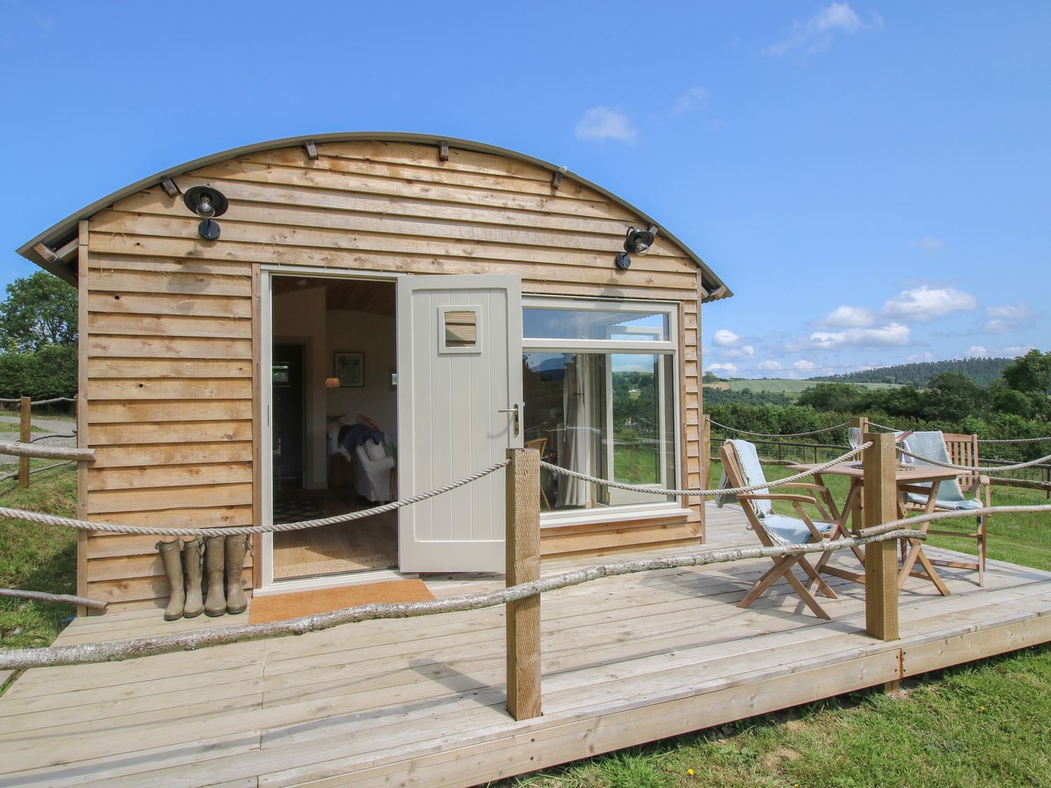 A wooden cabin with a deck and chairs at Owl's Hollow in Chapel Lawn near Clun