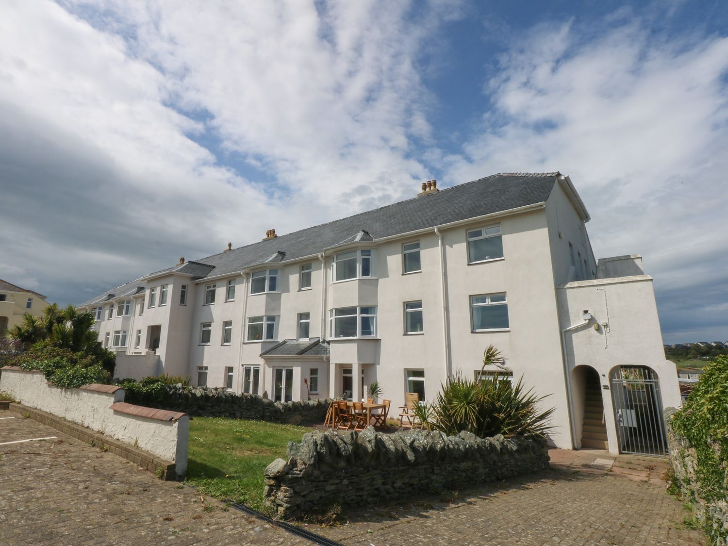 A building with multiple windows and a garden area at Cwtch y Môr in Trearddur Bay