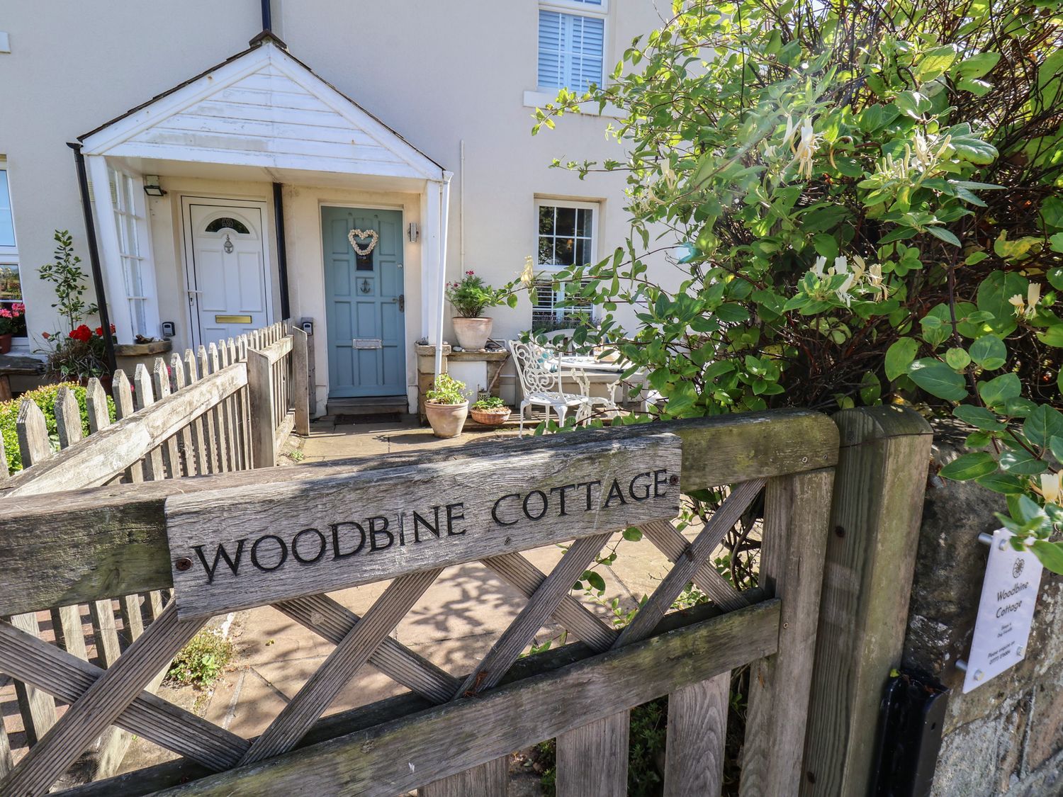 A front entrance with a blue door and gate at Woodbine Cottage in Whitby