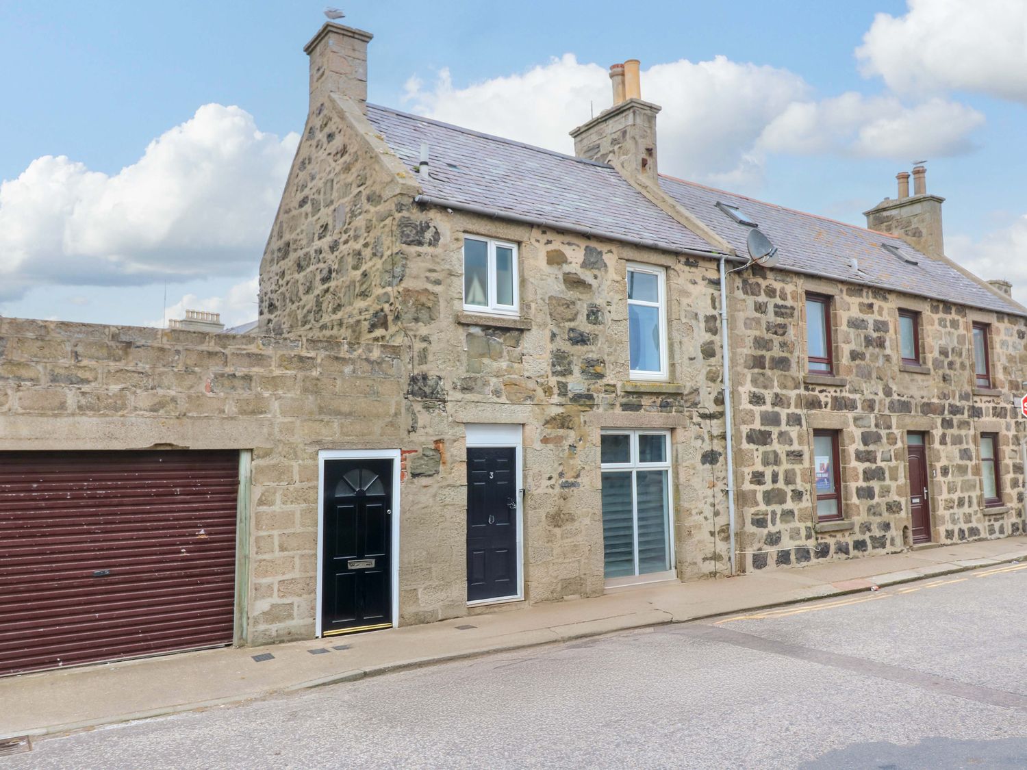 A stone house with a garage and multiple doors at 3 Caroline Place in Fraserburgh