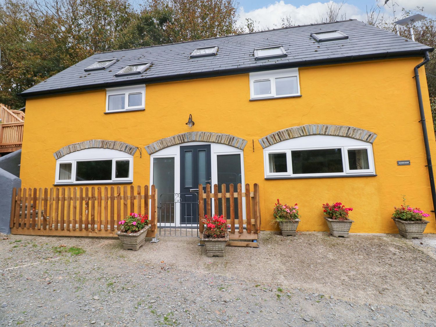 A house with a front yard and flowers at Pendre Barn Star near Cenarth