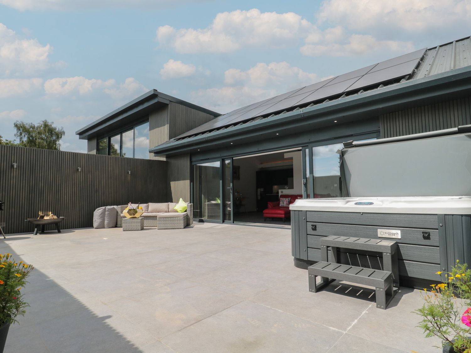 An outdoor area with a hot tub and seating at Noflash Malpal in Bishop Sutton