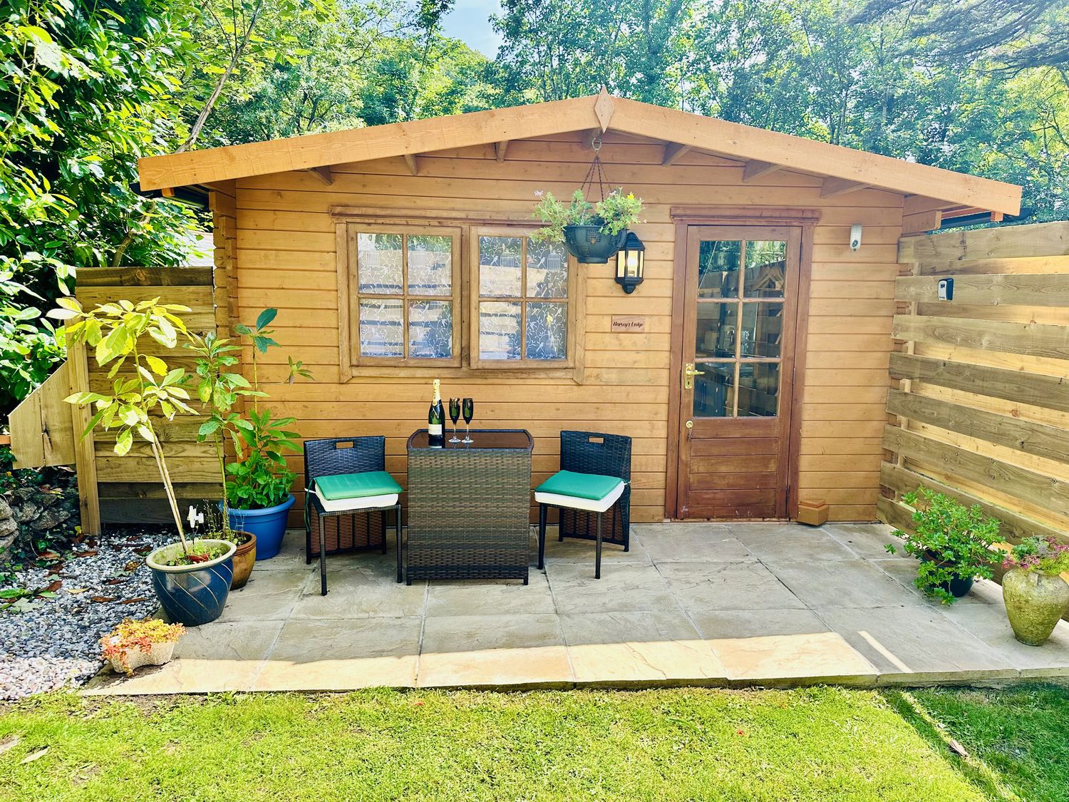 An outdoor area with a log cabin, table, and chairs at Harvey's Lodge in Lowertown, Helston