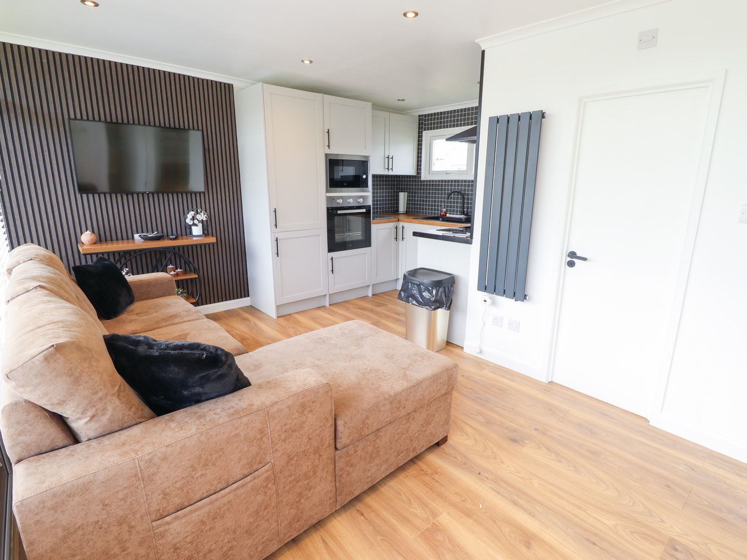 A living room with a sofa and kitchen area at 66 Cherry Park in Skegness