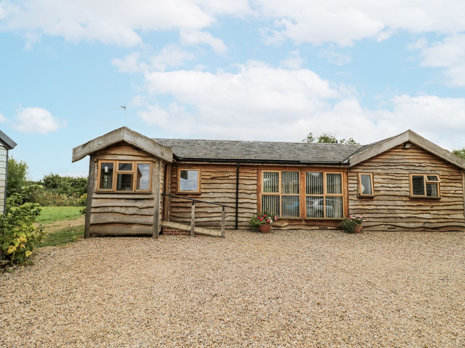 A cabin with wooden exterior and flower pots at Owl Barn in Banbury