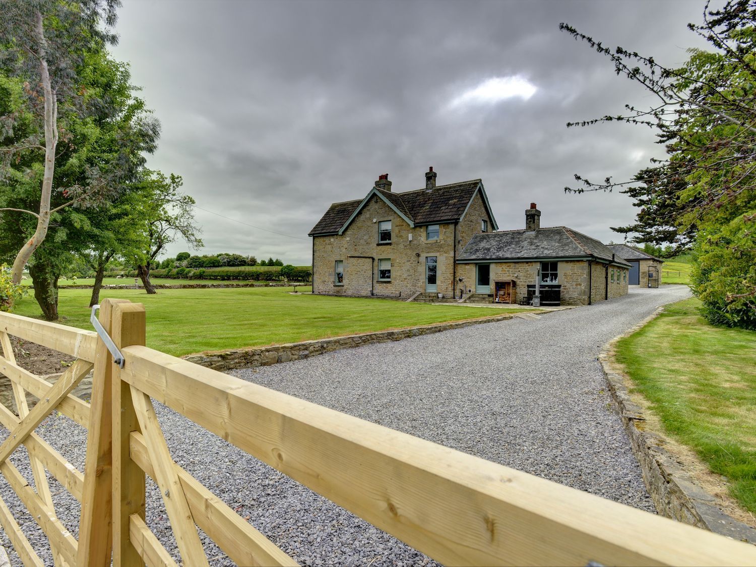 A house with a gravel driveway and garden at The Farm House in Aldbrough St. John near Barton