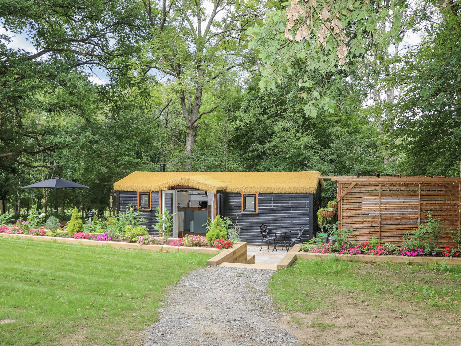 An outdoor area with a cabin and chairs at Charltons Hollow Cabin in Haywards Heath