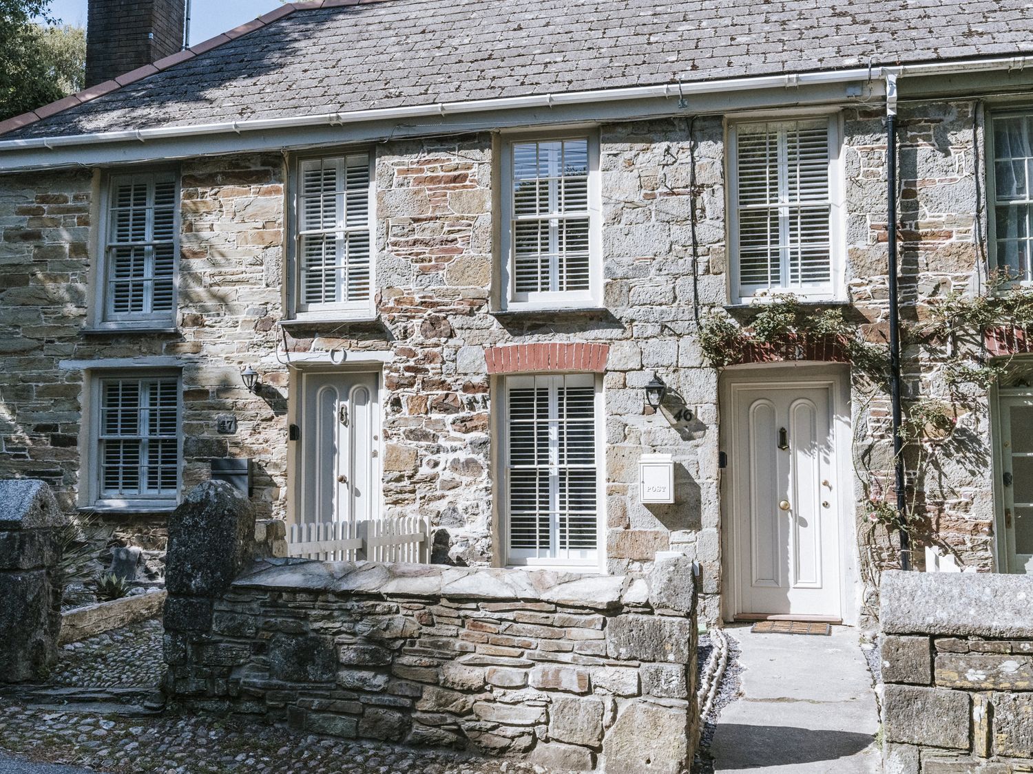 An outdoor view of a stone house with front door and windows at Bluck's cottage in St. Agnes