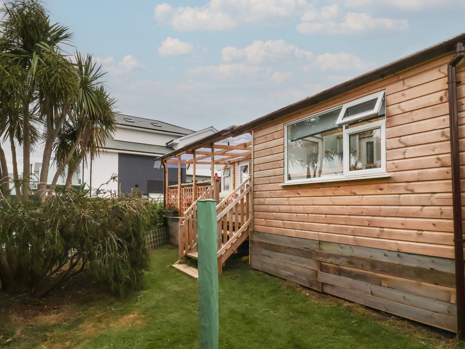 A wooden exterior of a building with stairs and palm trees at Big Bertha by the Sea Northam