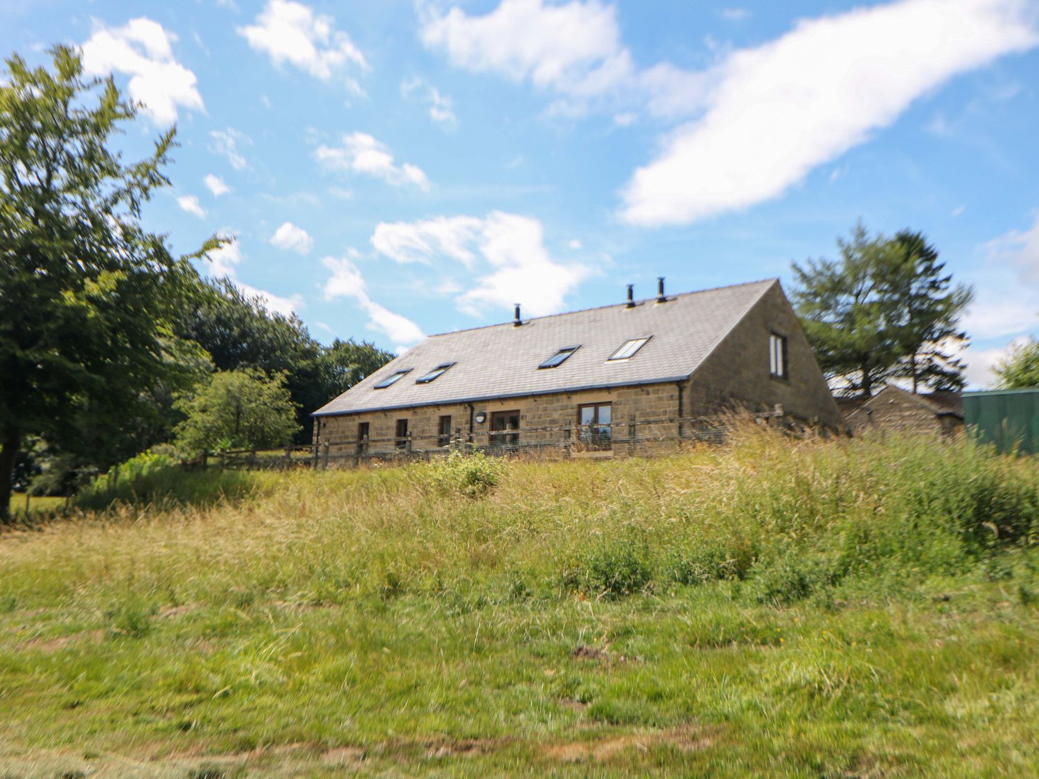 A house with grass and trees at Hollow Brook Cottage in Hope Valley