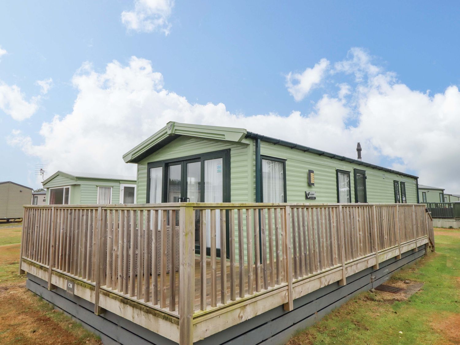 A green caravan with a deck at Sea Breeze C38 Dyffryn Seaside Estate Dyffryn Ardudwy