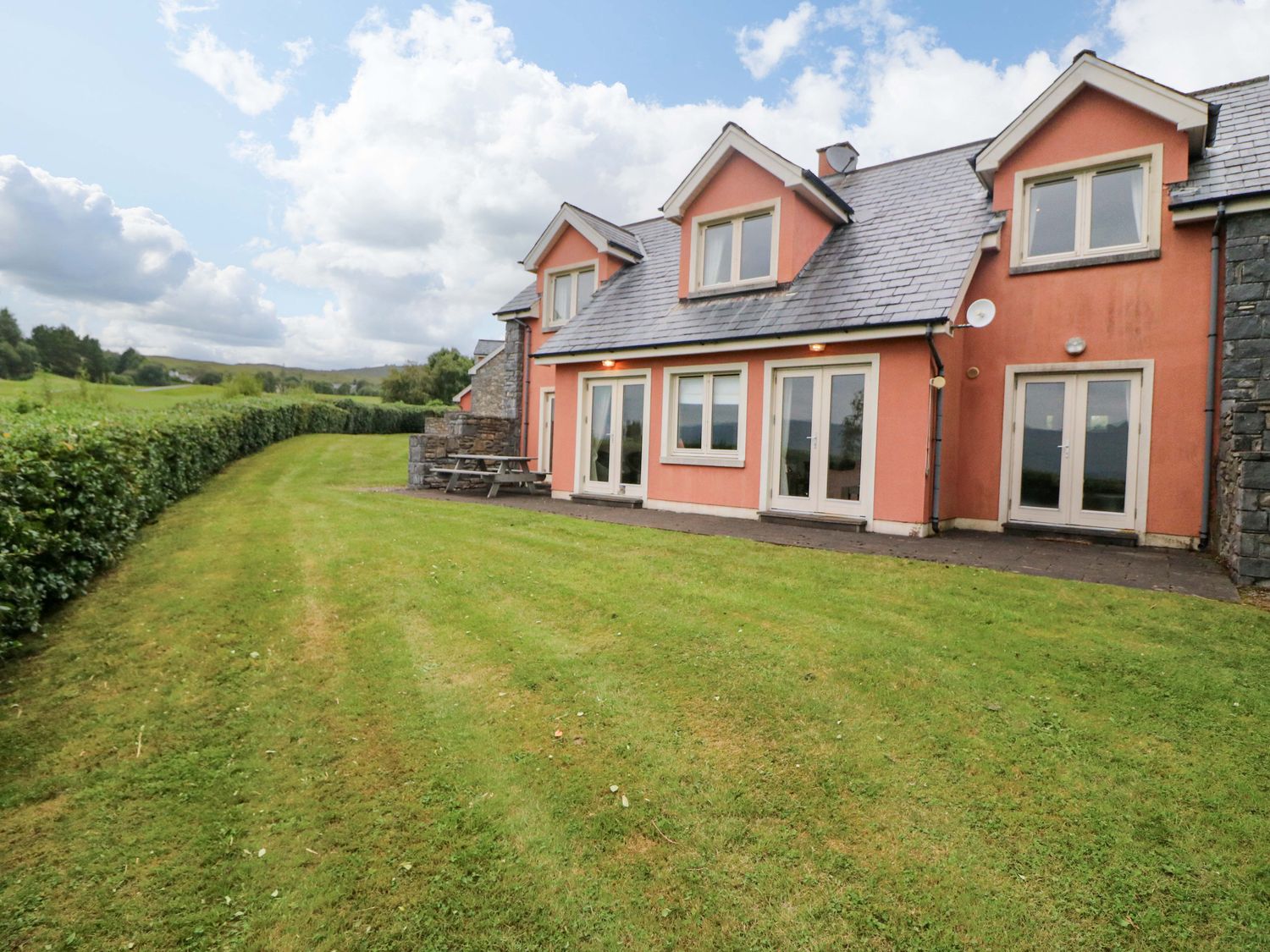 A house with a patio and grass yard at 25 Ring of Kerry Holiday Cottages in Kenmare
