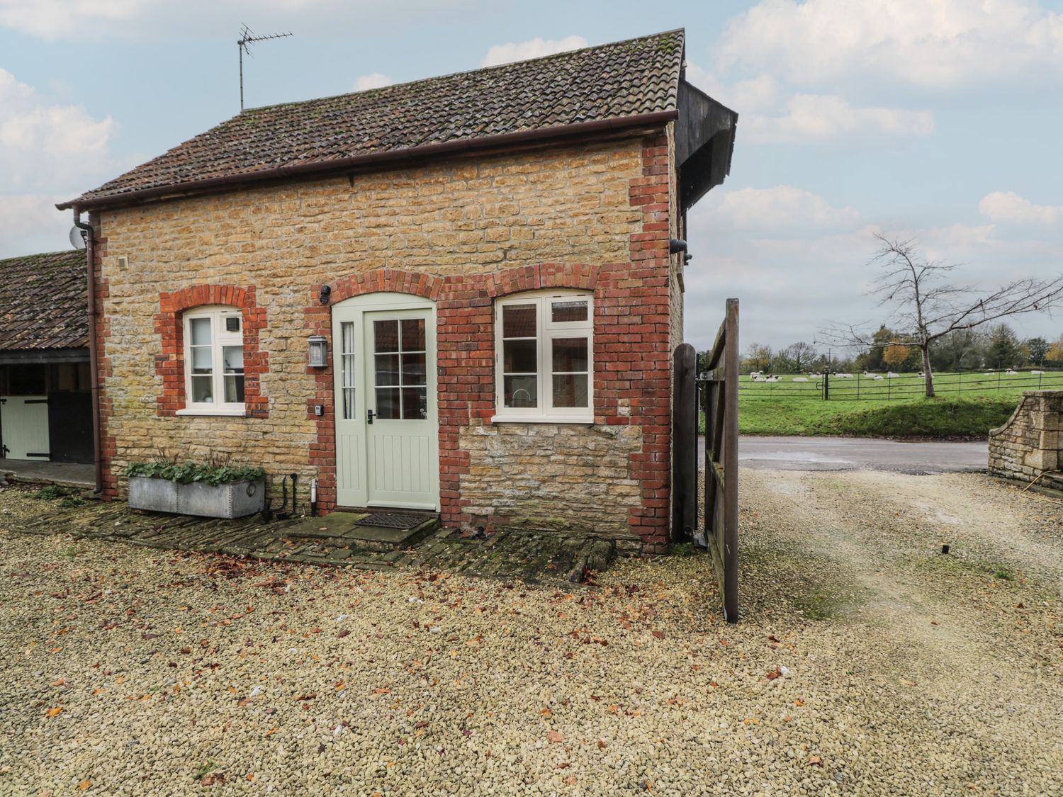 A cottage with green door and stone exterior at Granary Cottage in 