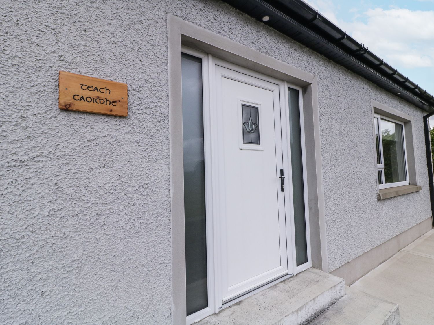 An entrance with a white door and a wooden sign at Teach Caoimhe in Falcarragh