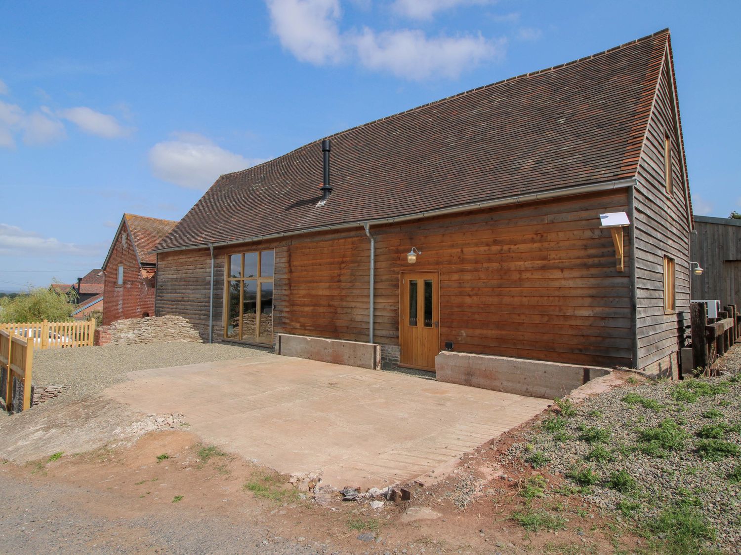 A wooden building with large windows and parking space at Crook Barn in Tenbury Wells